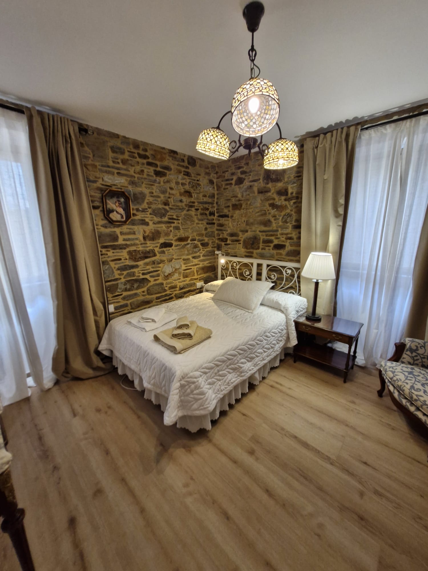 Habitación con cabecero de forja y muro de piedra gallega