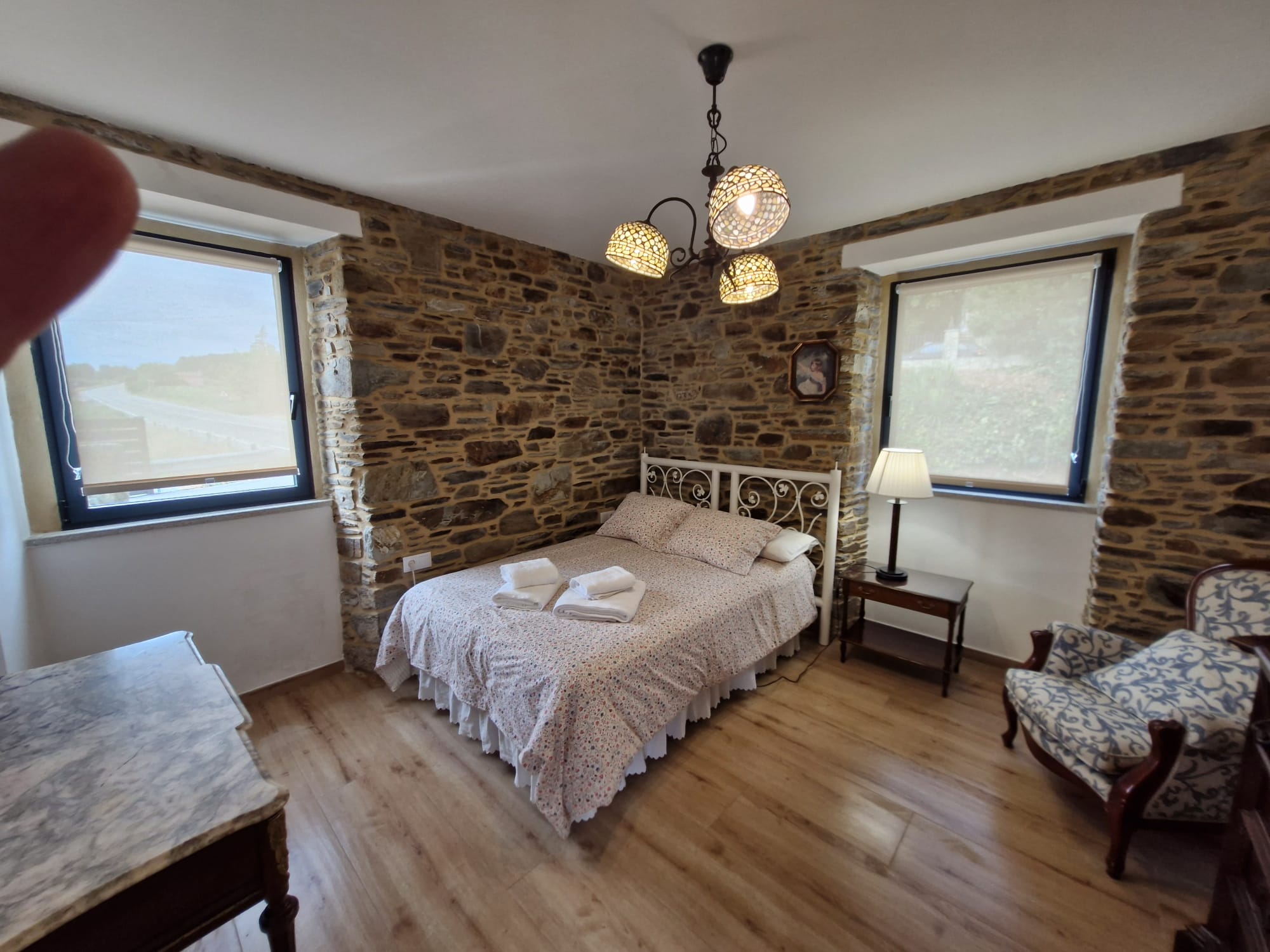 Tercera habitación con cabecero de forja blanca y muro de piedra