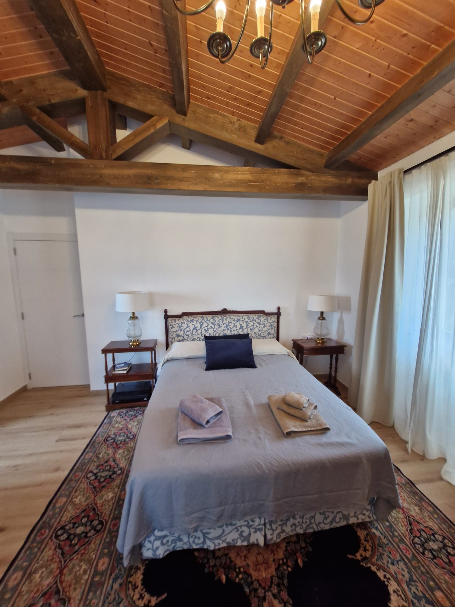 Habitación principal con cabecero tapizado y vigas de madera