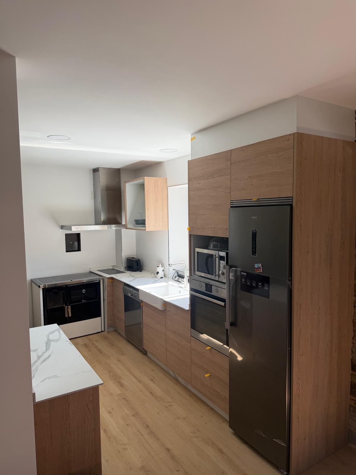 Cocina de madera clara con electrodomésticos en acero