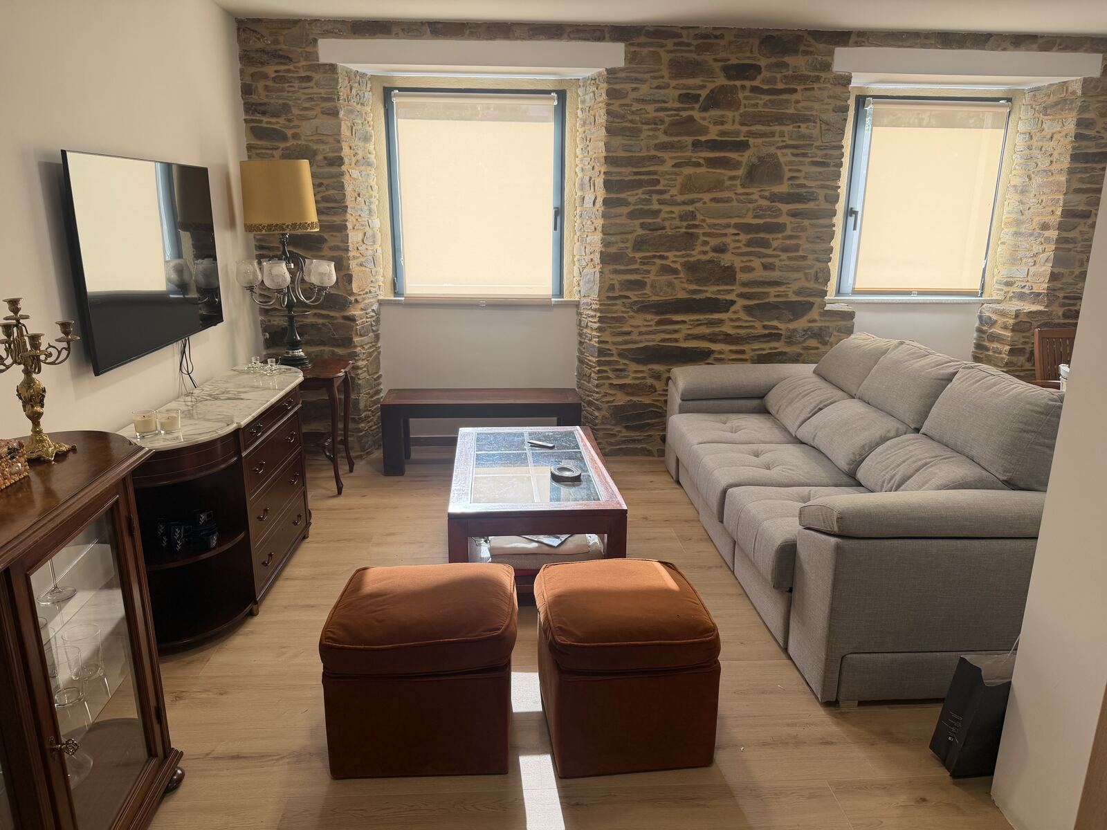 Salón con sofá gris y muro de piedra