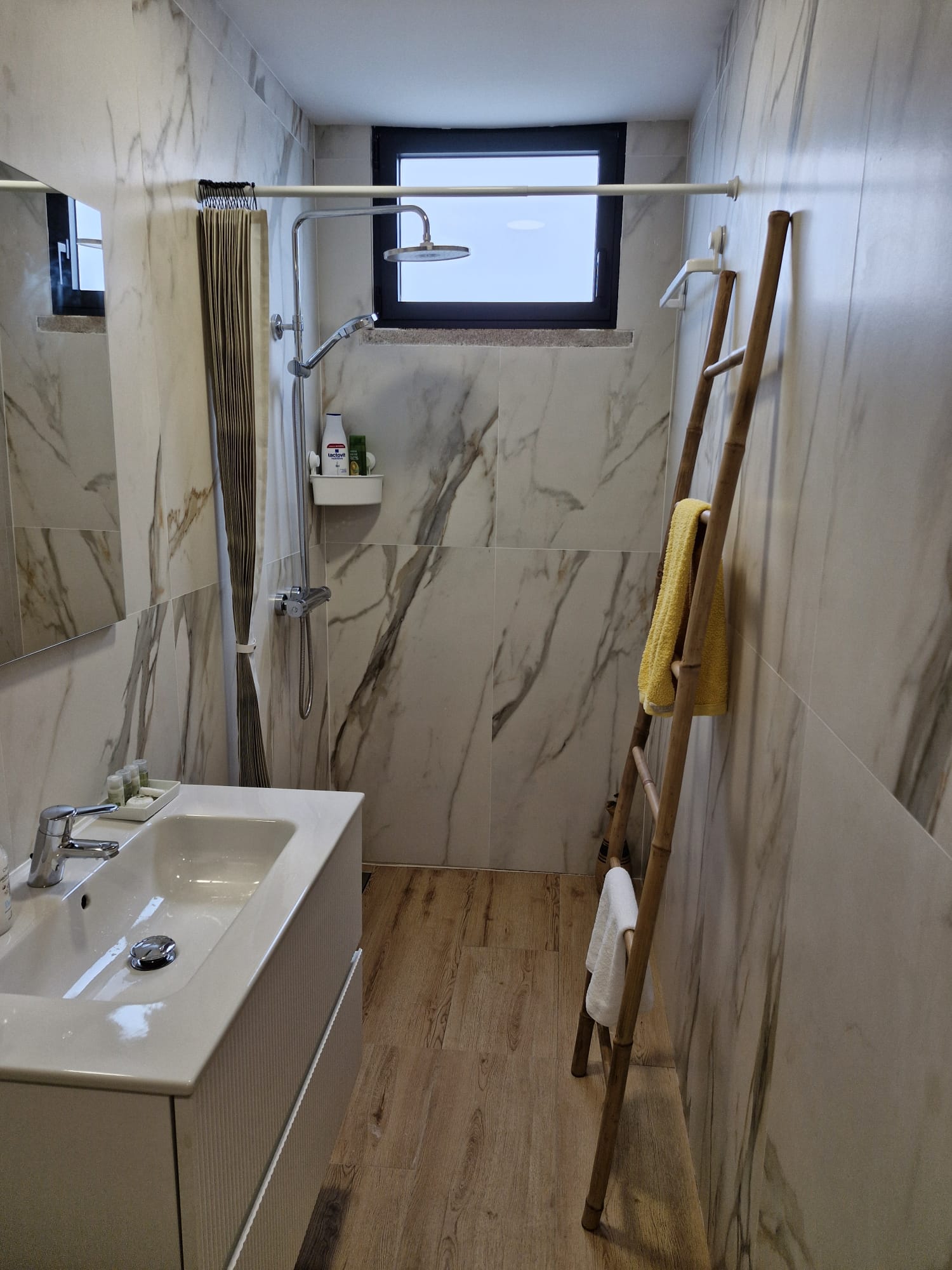 Ducha de mármol con escalera de toallas de bambú de la habitación de forja